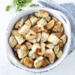 Baked buttery and garlic croutons with herbs in a white dish.
