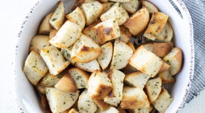 Baked buttery and garlic croutons with herbs in a white dish.