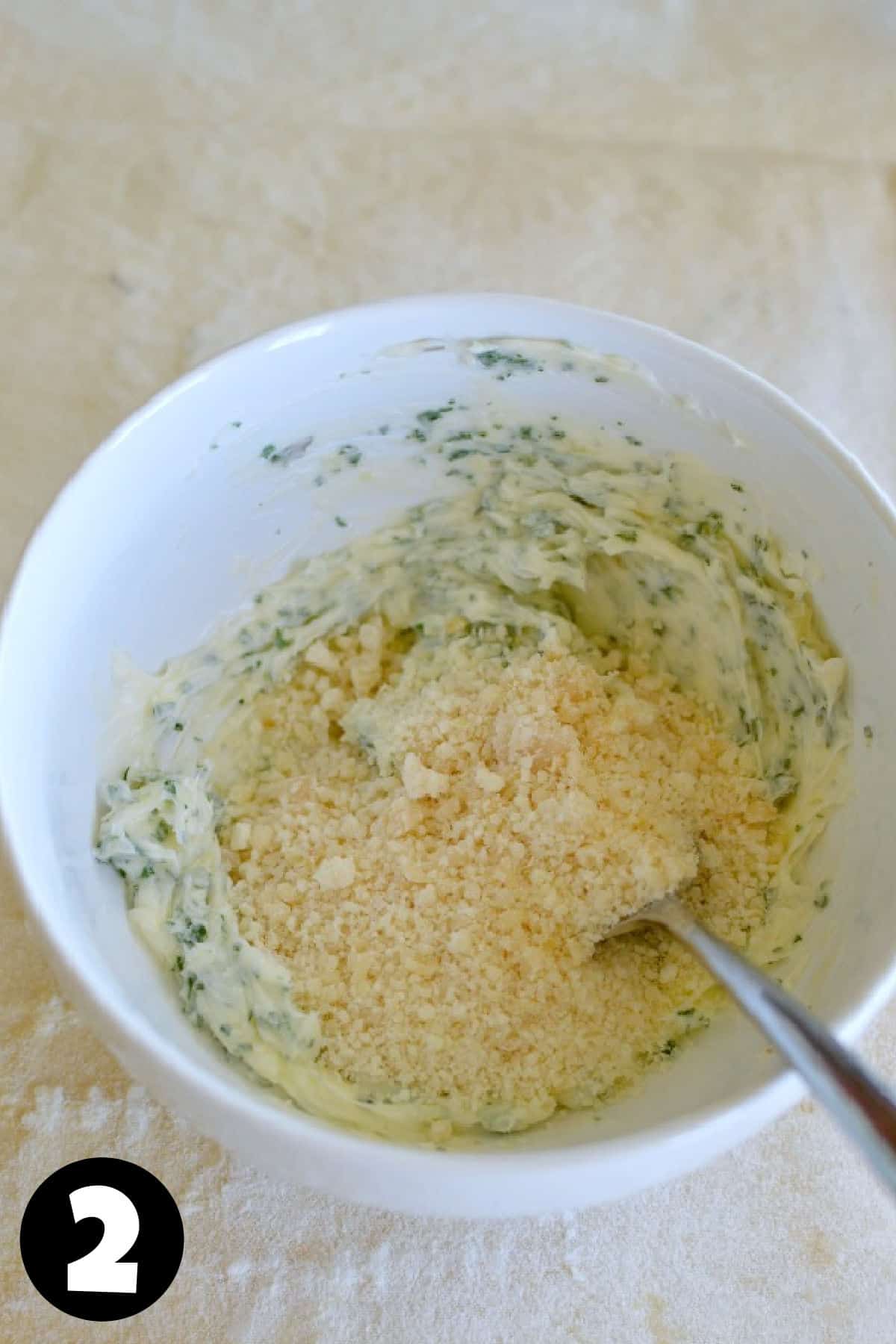 A bowl with butter, parmesan cheese, garlic, and herbs.