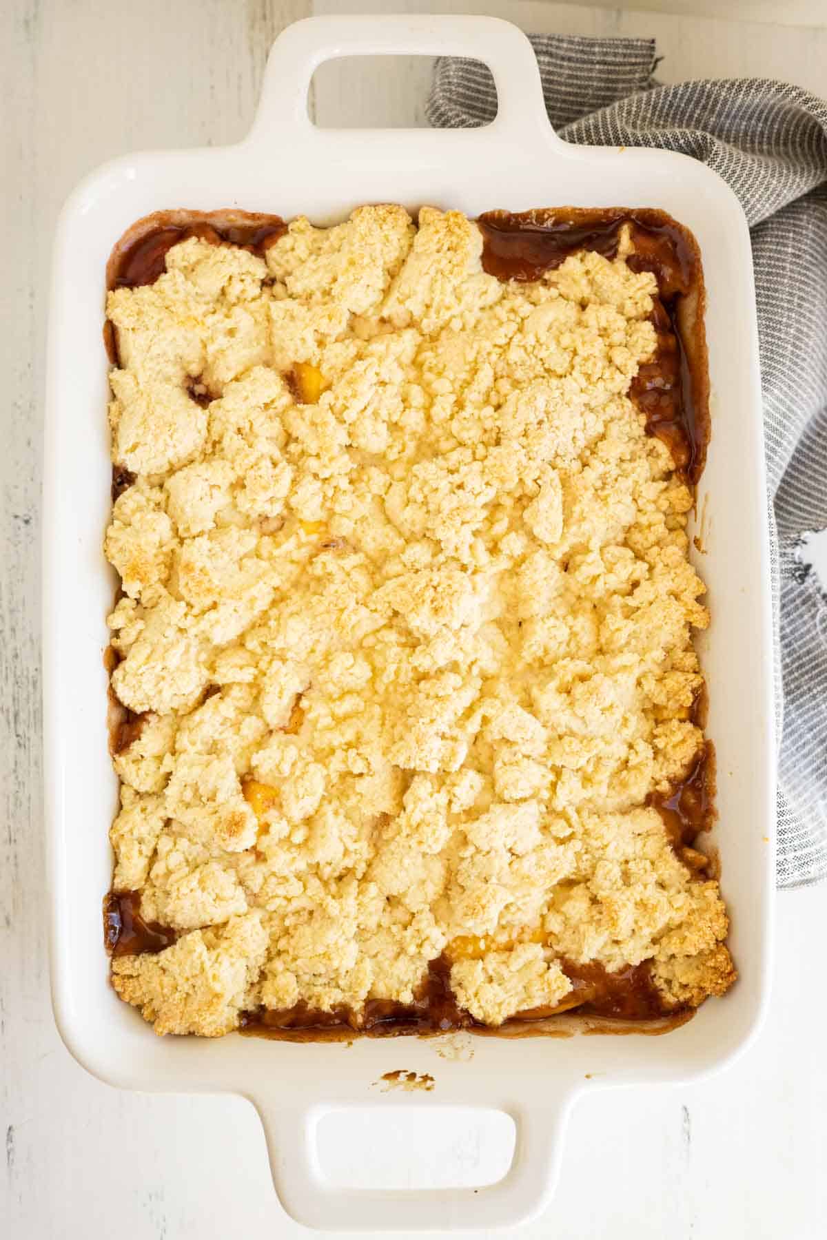 Peach cobbler in a white baking dish.