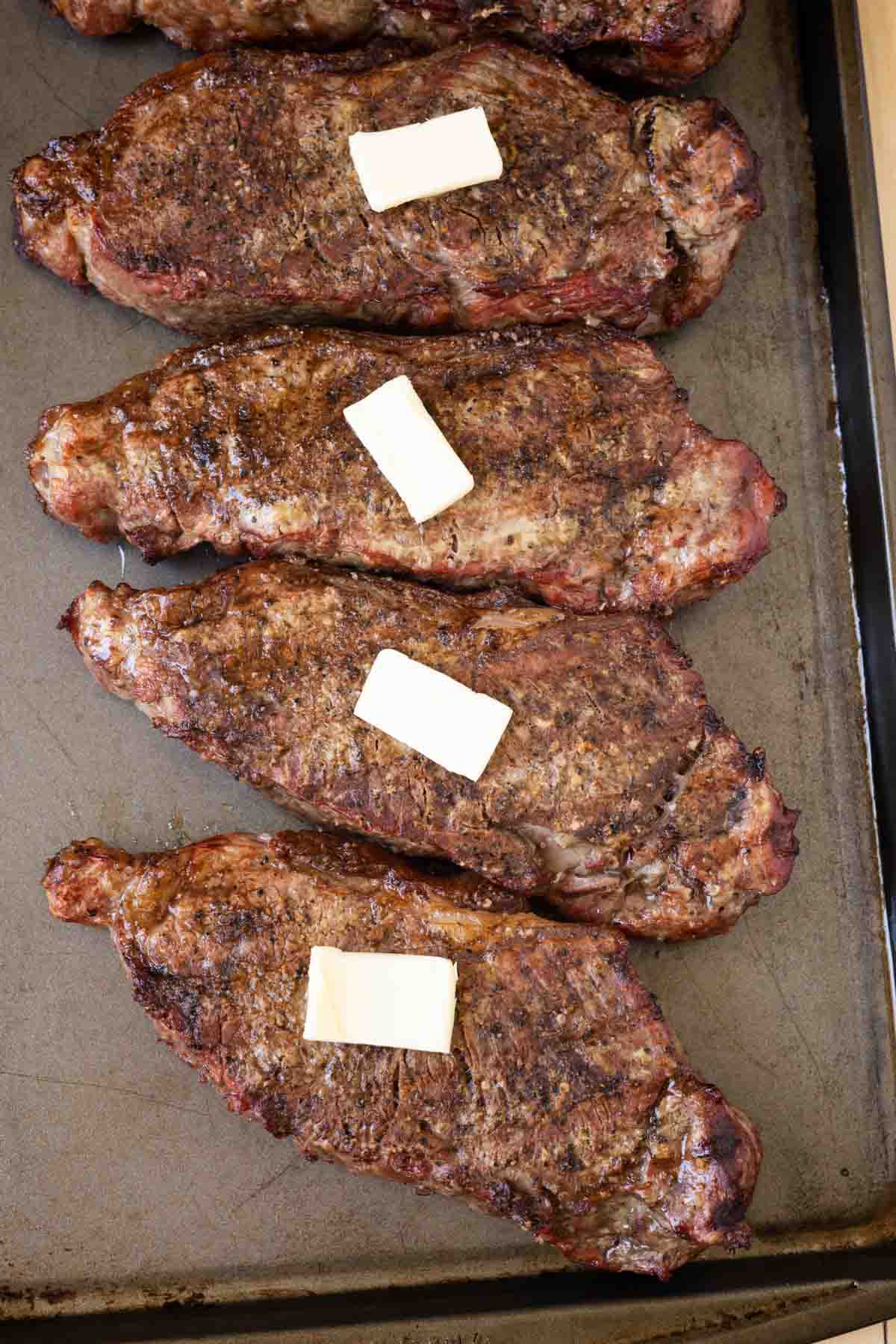 Grilled ny strip with a slice of butter on a baking sheet. 