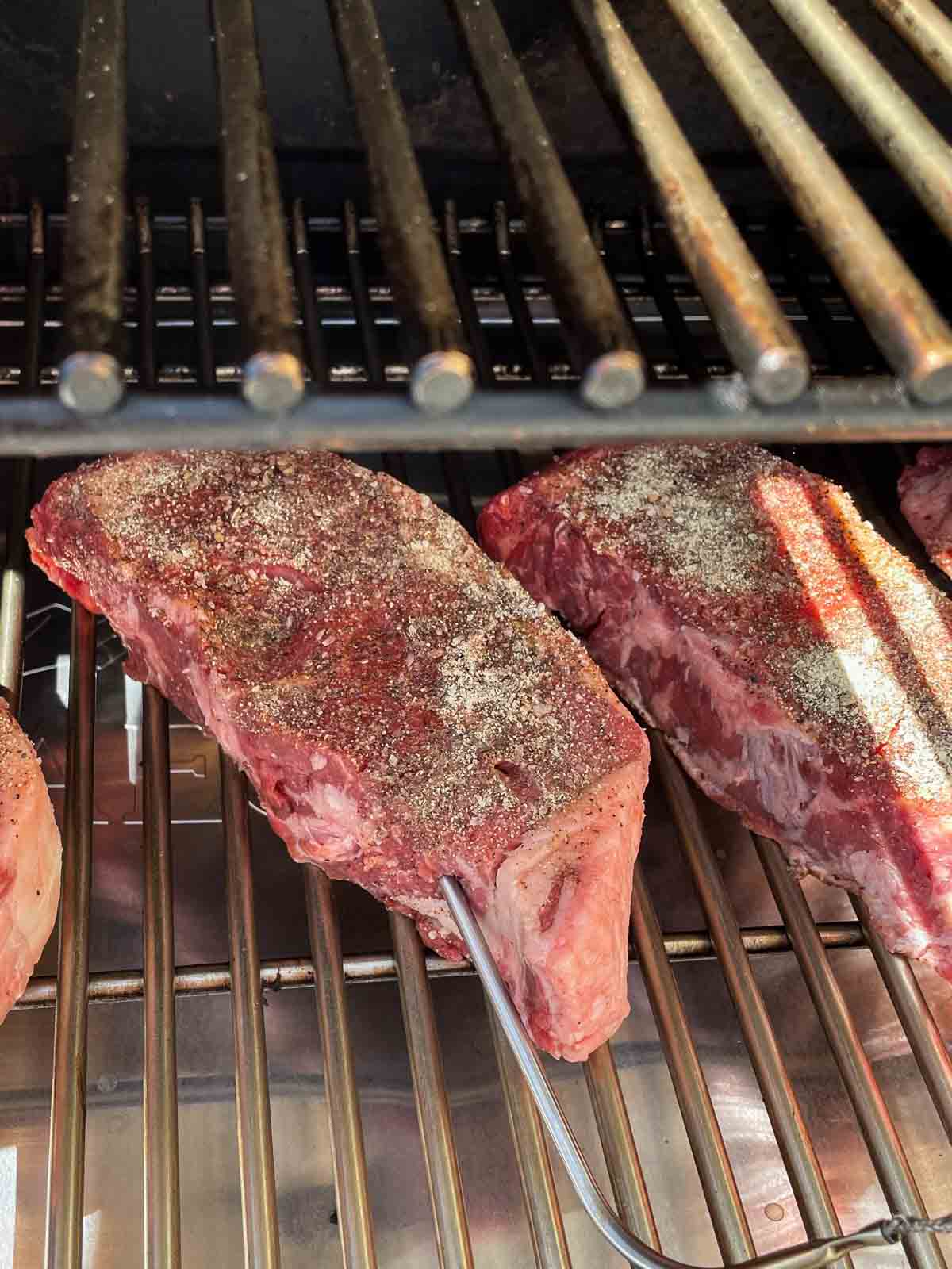 New York Steak on a smoker grill grate.