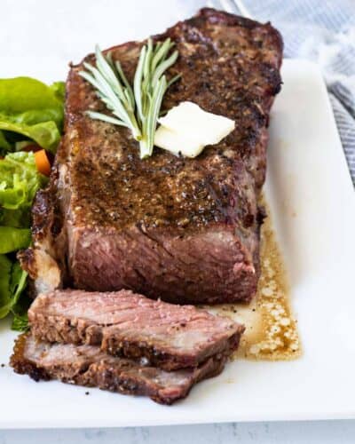 Grilled steak on a place with herbs on top.