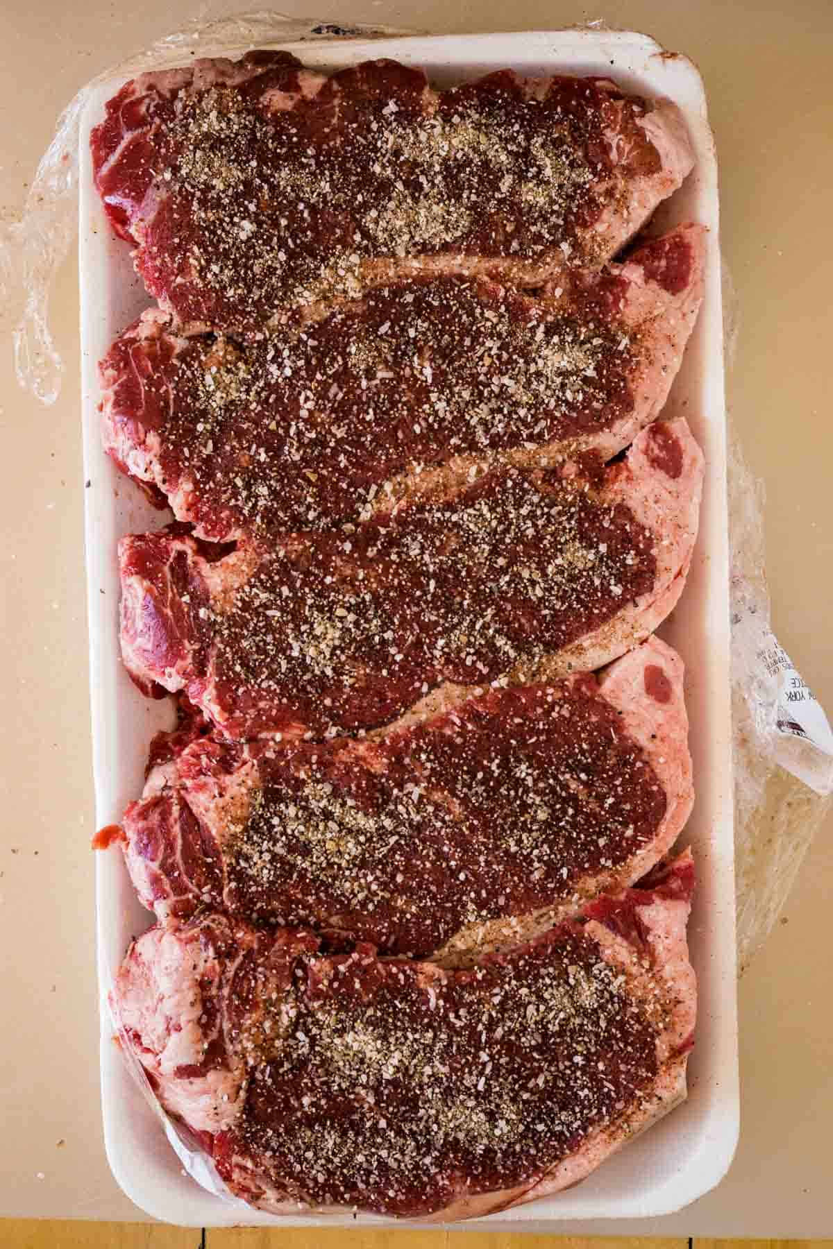 Raw ny strip steaks with salt and pepper.