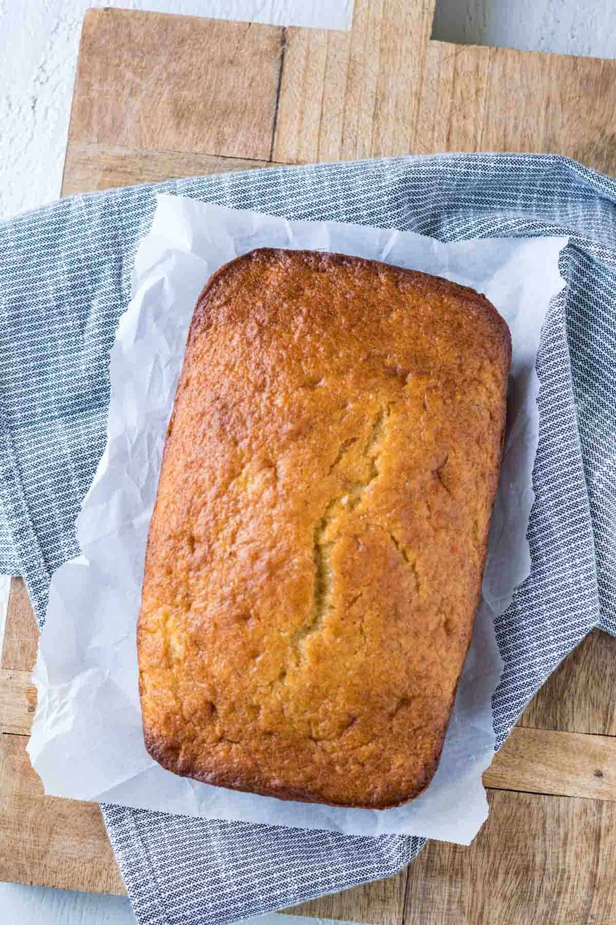 A loaf of yellow cake mix banana bread on a wooden cutting board.