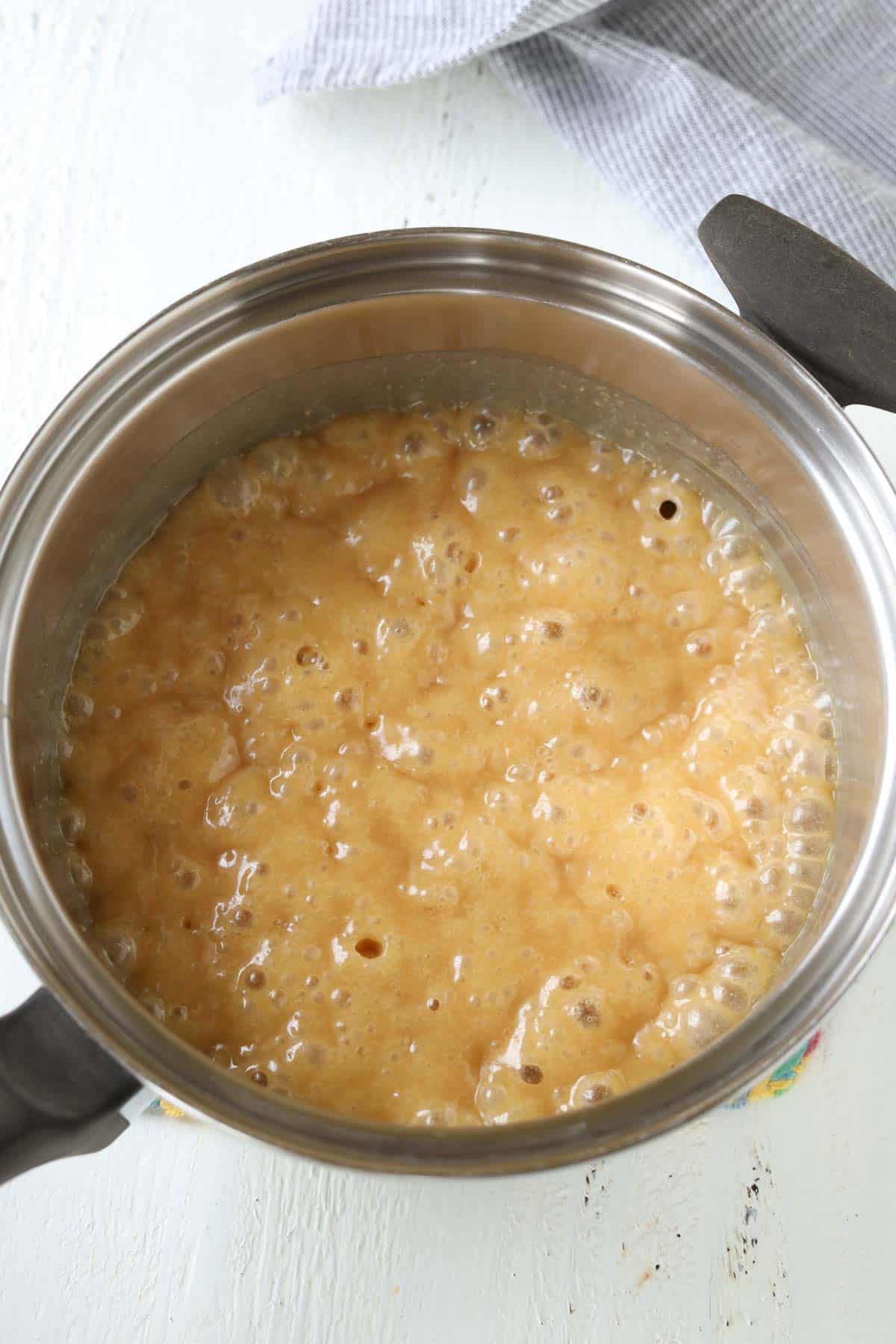 A boiling caramel mixture in a saucepan.