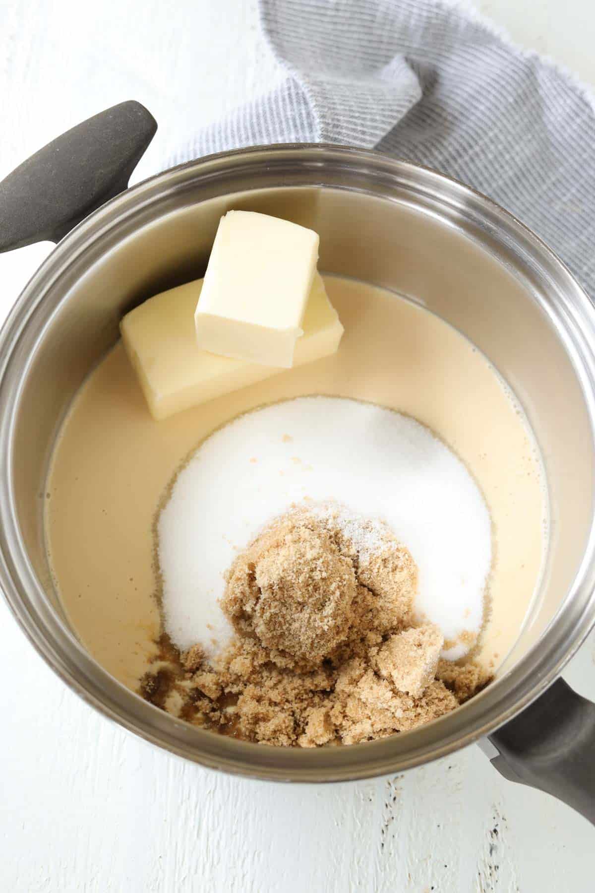 A medium saucepan with brown sugar, white sugar, butter, and evaporated milk. 
