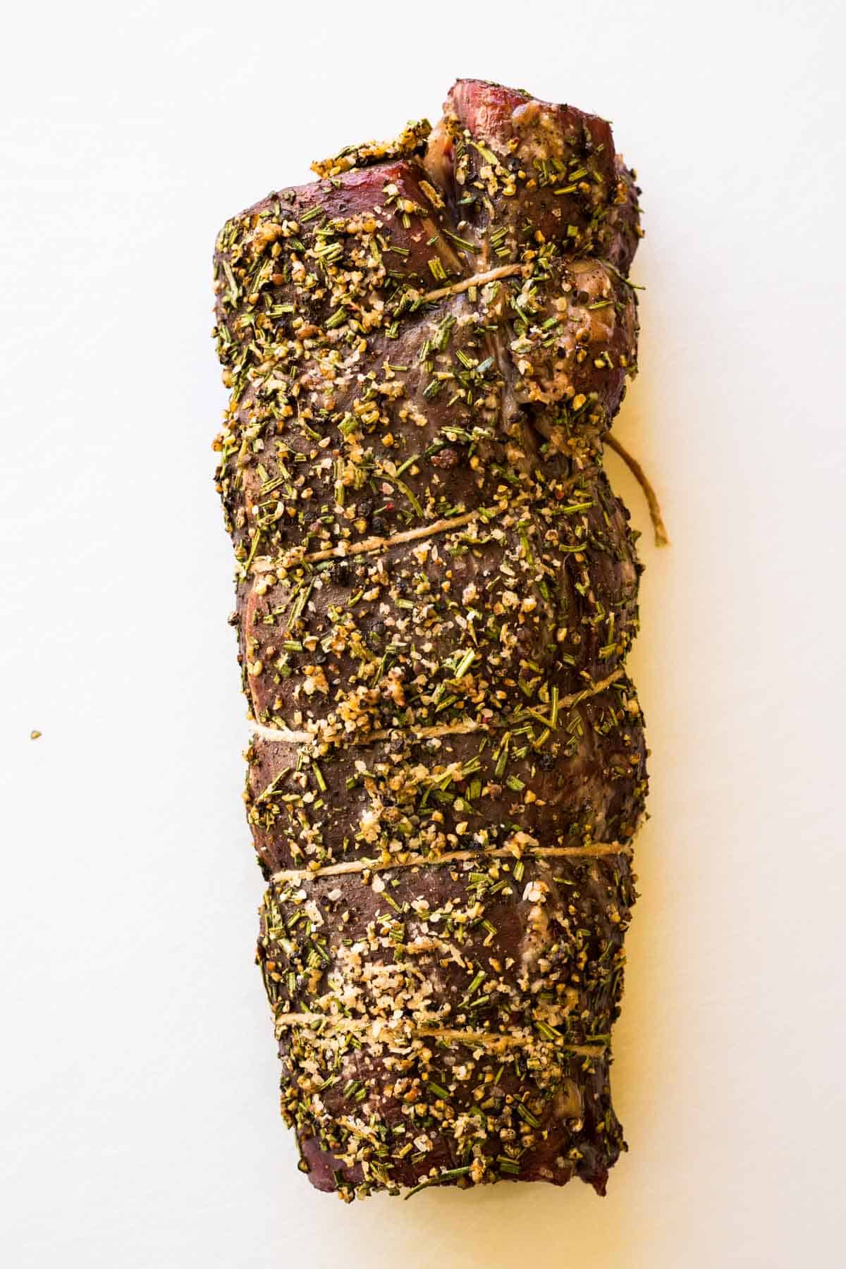 A whole herb crusted beef tenderloin wrapped with butcher's twine.