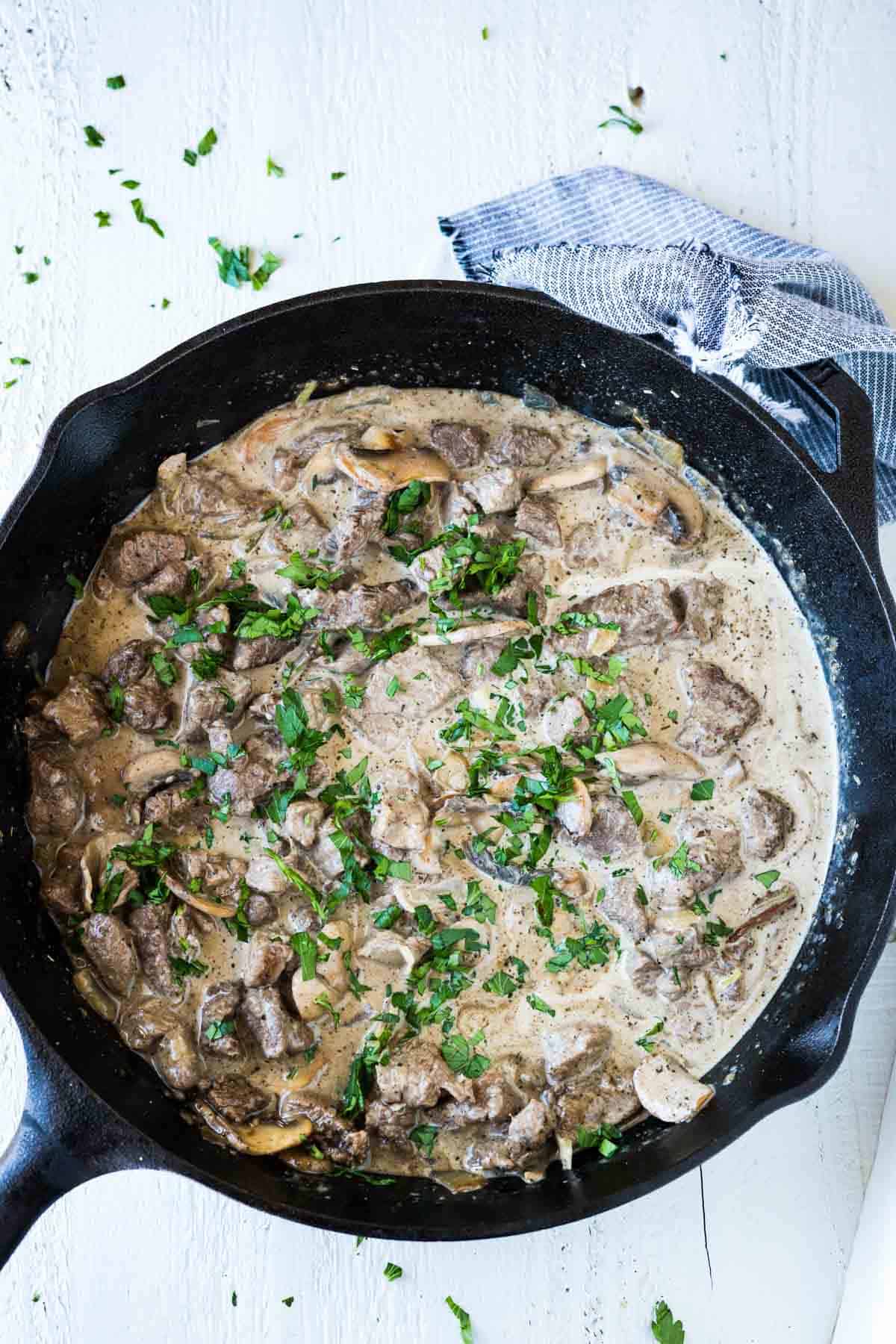 Beef tenderloin tips in a mushroom gravy sauce in a cast iron skillet.