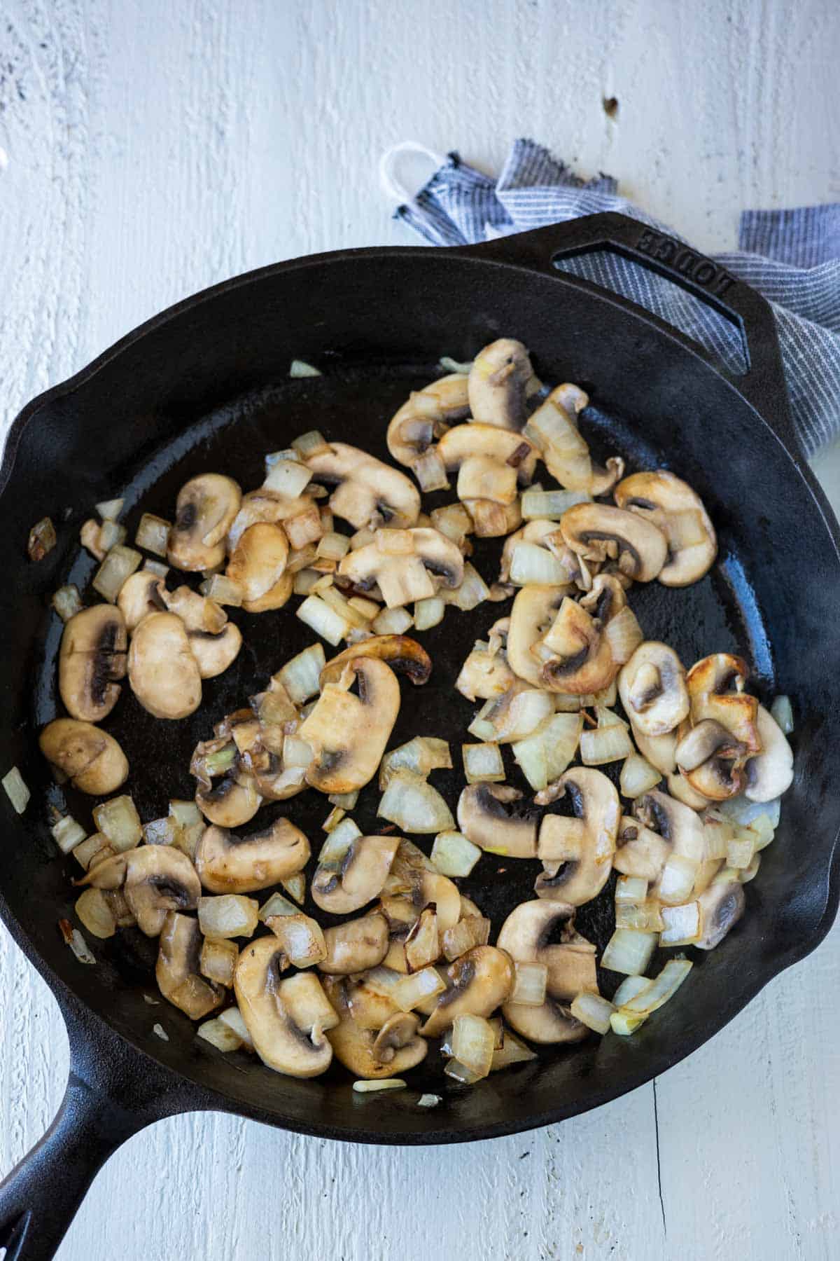 Golden brown and tender sliced mushroom and onions in a cast iron skillet.