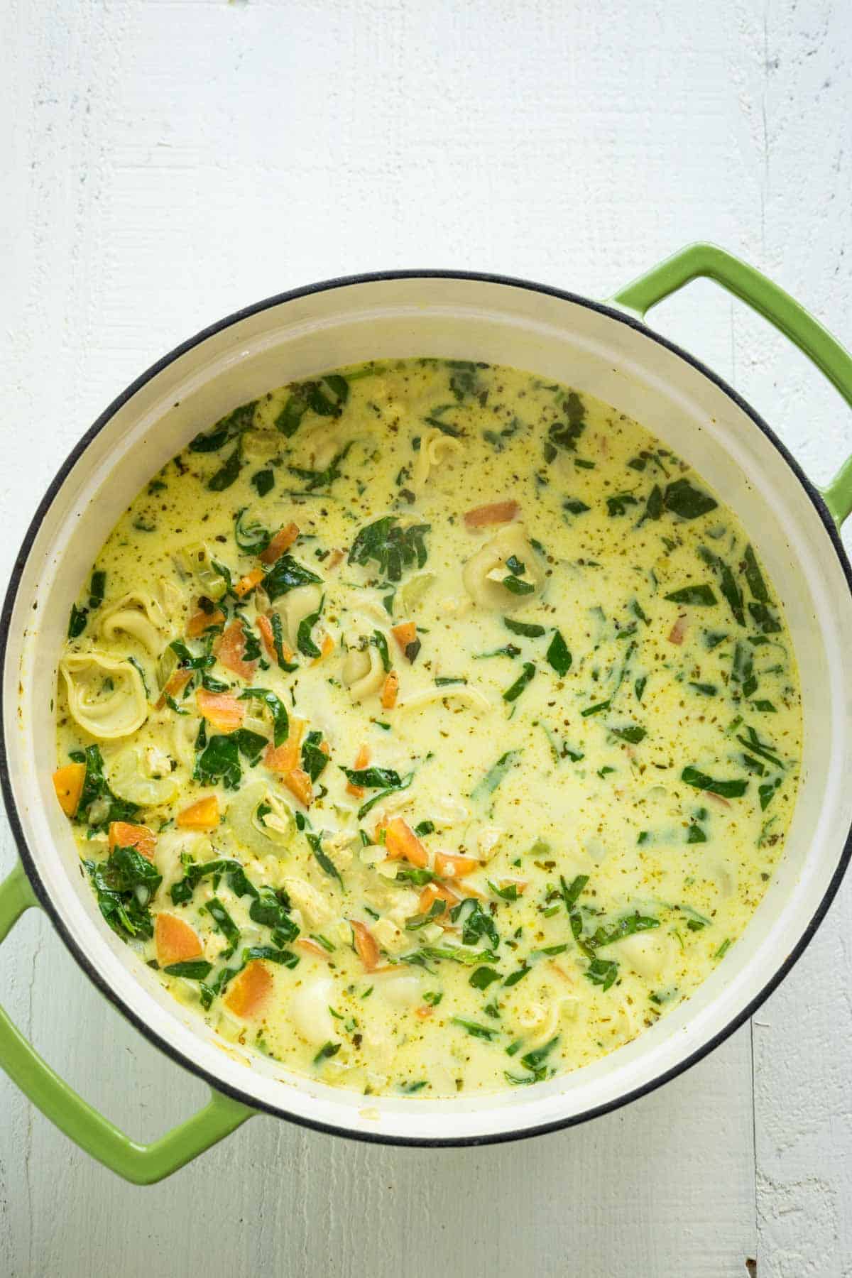 A large stock pot with creamy chicken spinach and tortellini soup.