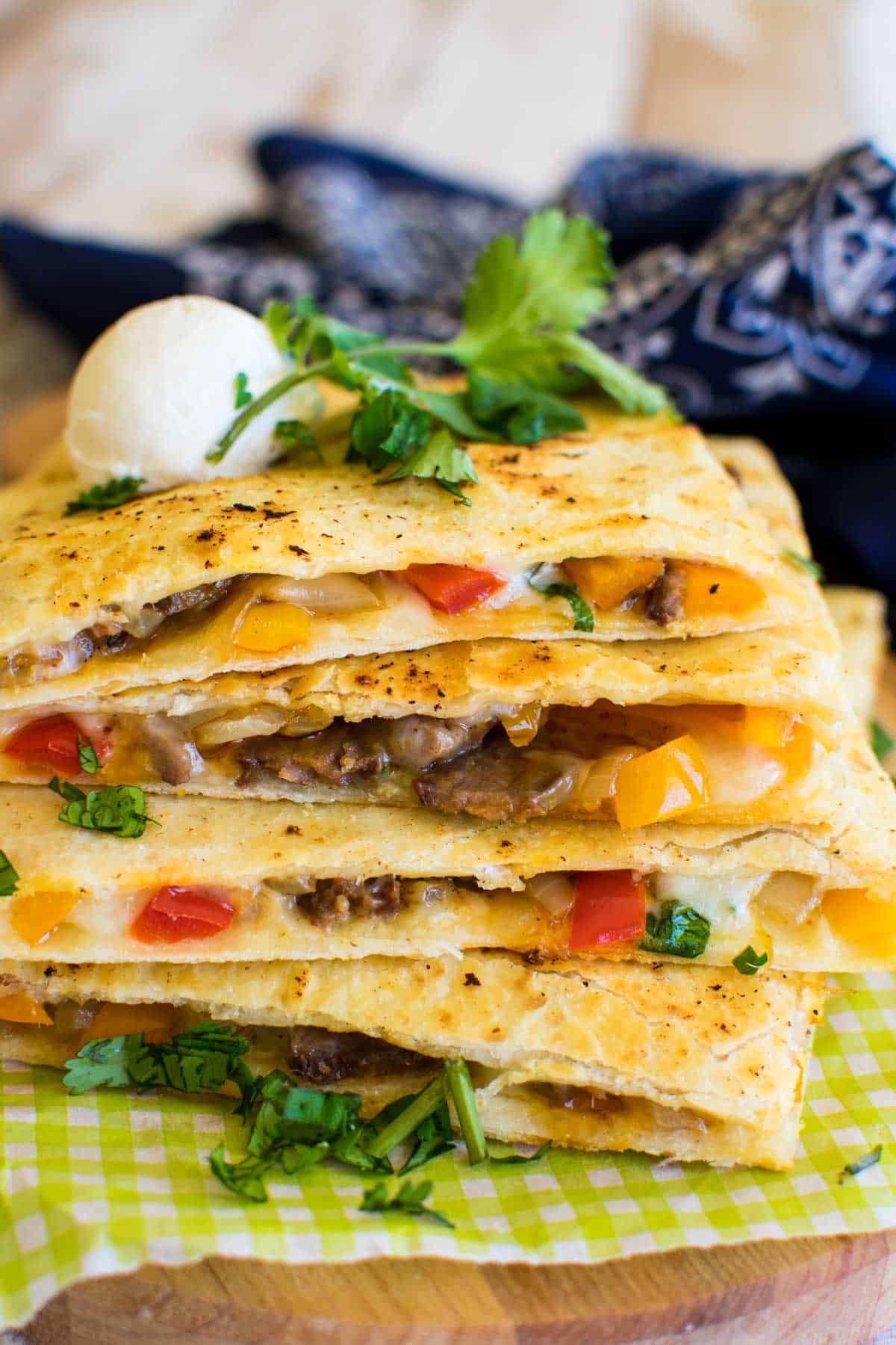 Wedges of steak quesadilla stacked up with fresh herbs and cheese.