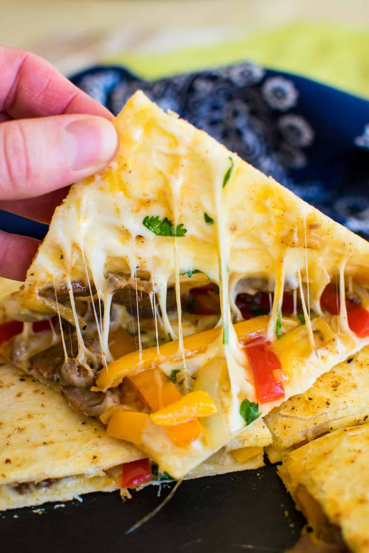 A steak and cheese quesadilla that's being opened to show gooey cheese.