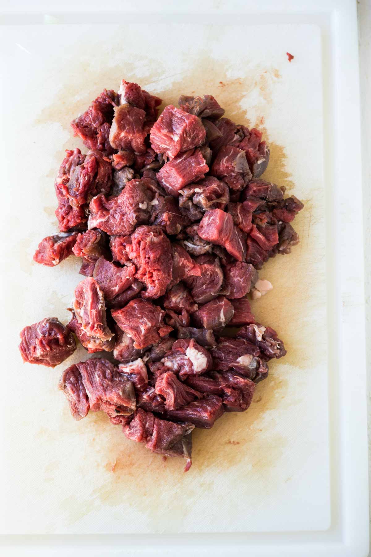 Pieces of raw tenderloin tips on a cutting board.
