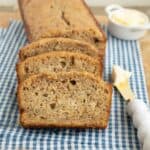 Slices of a loaf of banana bread on a blue and white checkered napkin.