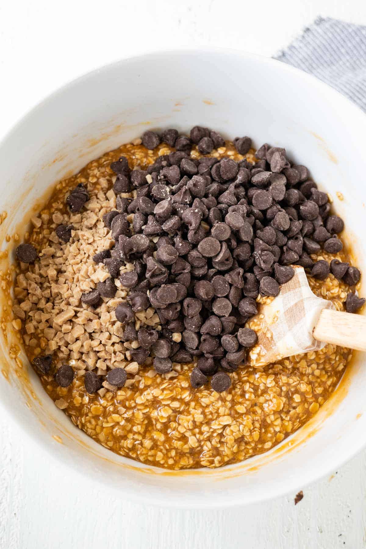 A caramel no bake cookie mixture with chocolate chips and toffee chips in a mixing bowl.