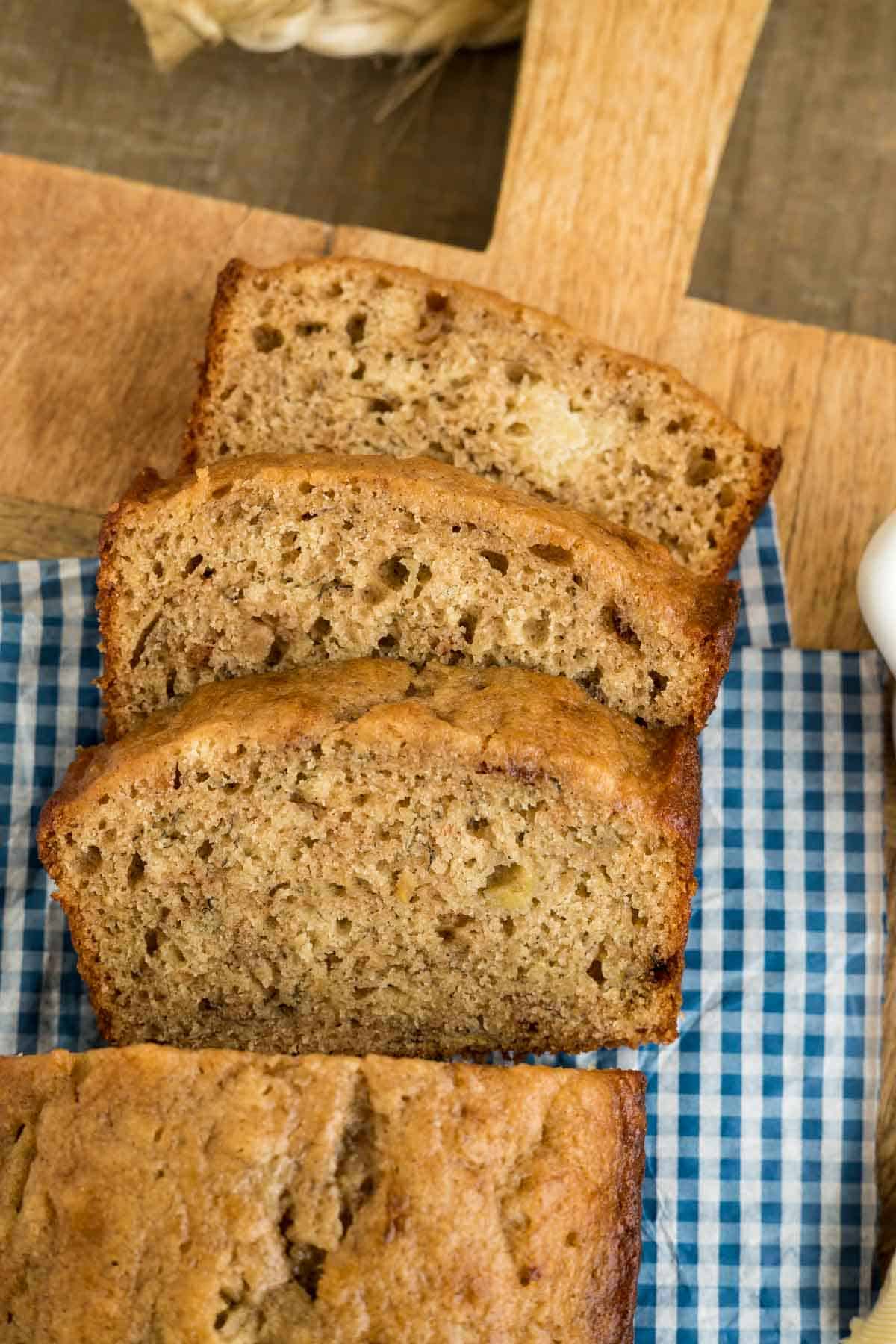 Sliced Greek yogurt banana bread on a blue and white gingham napkin.