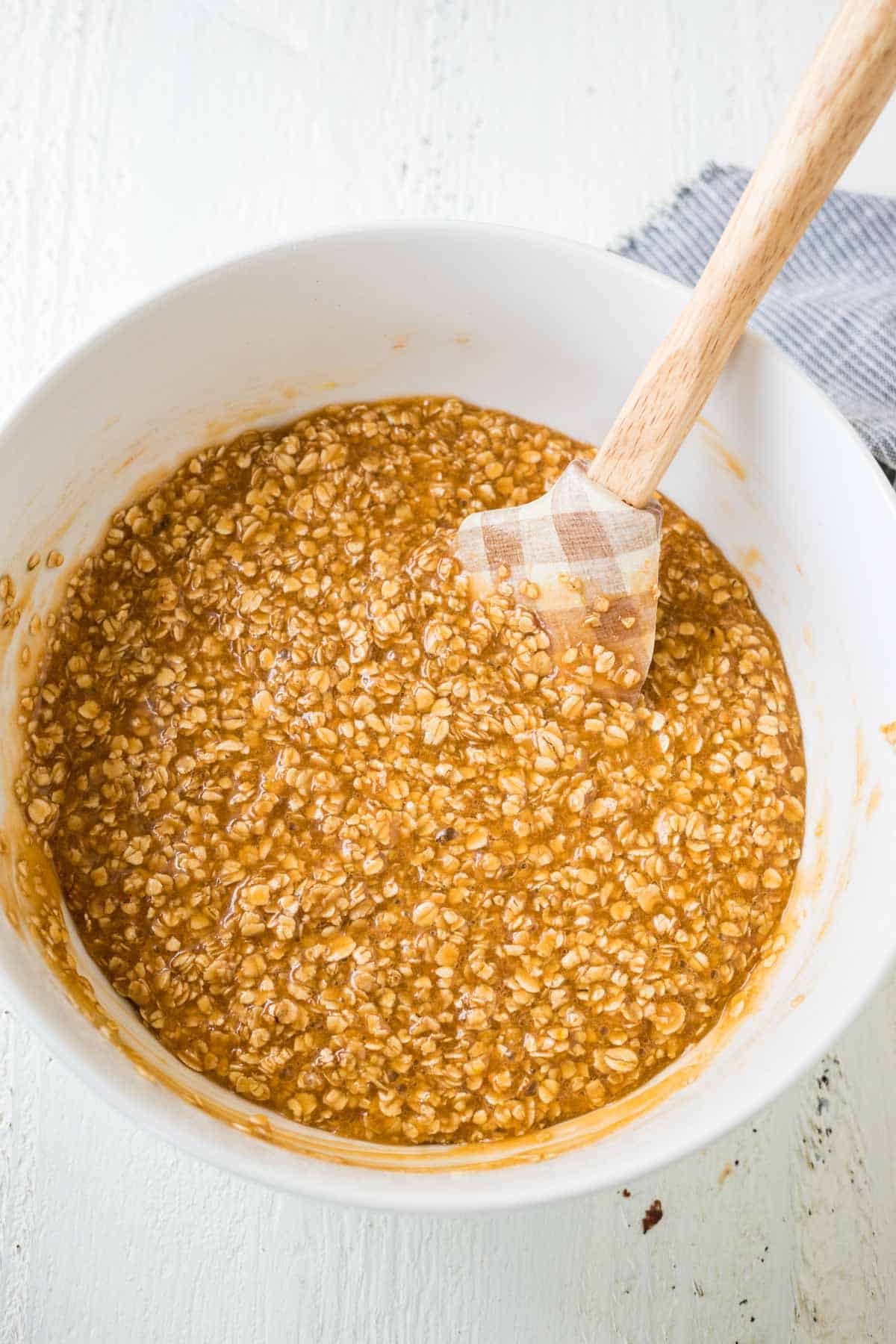 Oats in a caramel mixture in a mixing bowl.