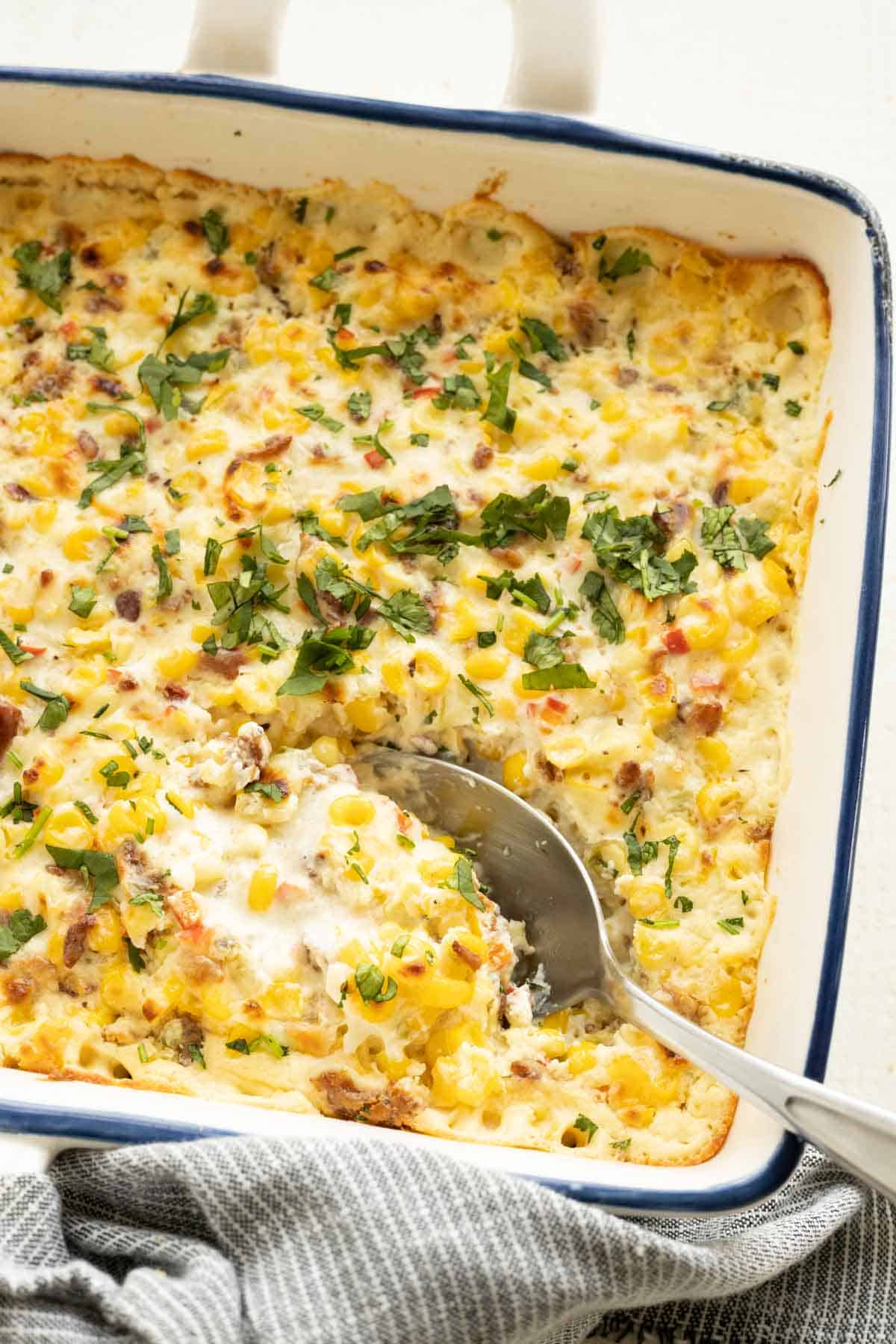 Baked corn dip with a spoon in the casserole dish.