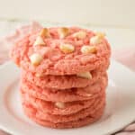 A stack of strawberry white chocolate chip cookies on a plate.