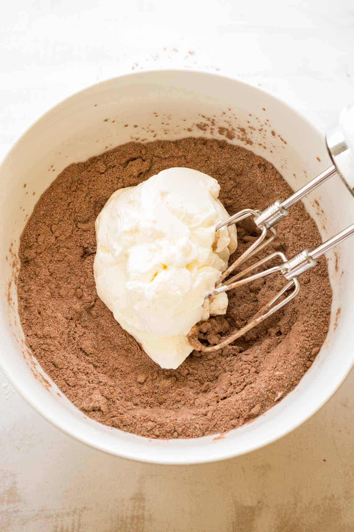 Plain Greek yogurt with dry ingredients for making brownie batter.