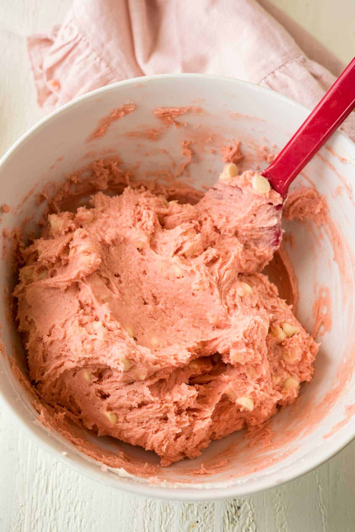 Strawberry cookies dough with white chocolate chips in a mixing bowl.