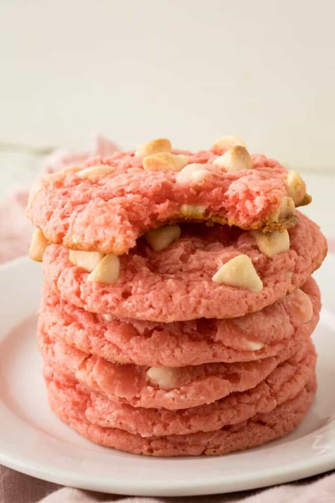 A stack of pink strawberry cheesecake cookies with white chocolate chips.