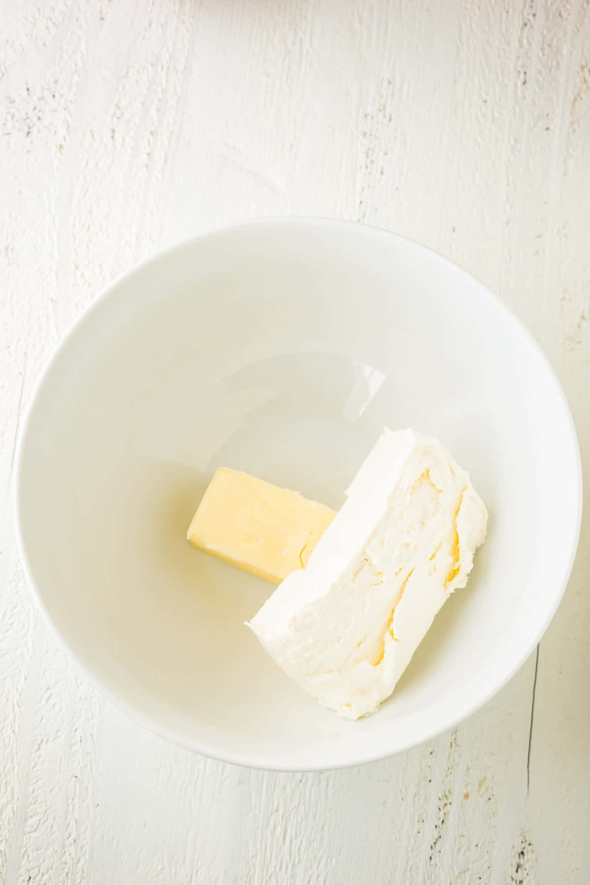 Cream cheese and and cube of butter in a mixing bowl.