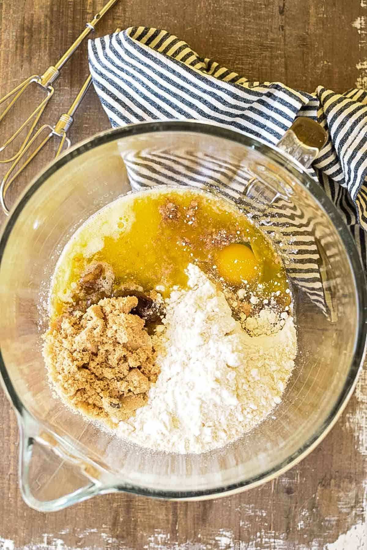A dry white cake mix, melted butter, and brown sugar in a mixing bowl for an electric mixer.