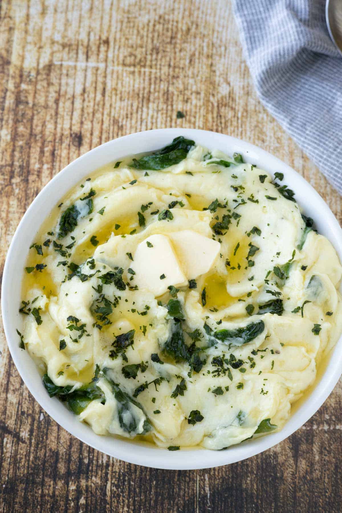 A bowl of spinach mashed potatoes with butter on top.