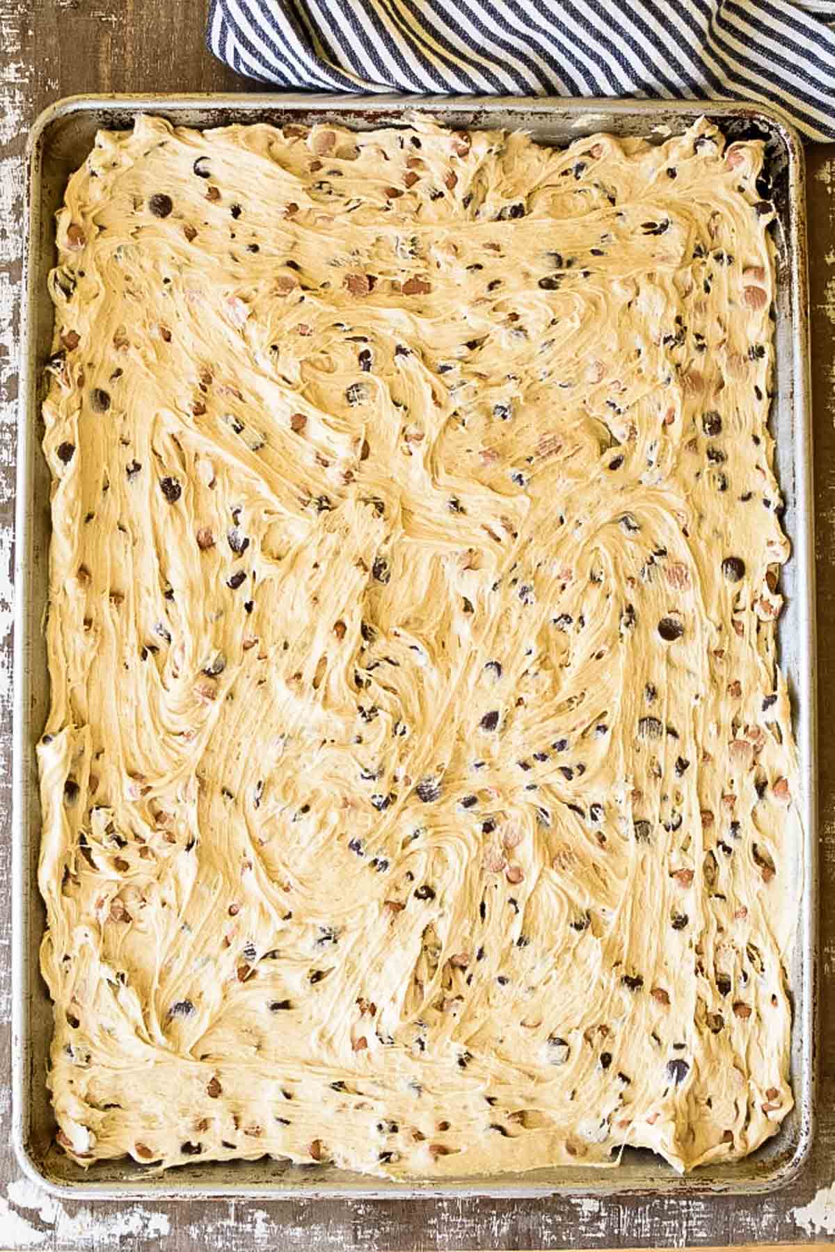 A sheet pan with chocolate chip cookie dough spread in it.