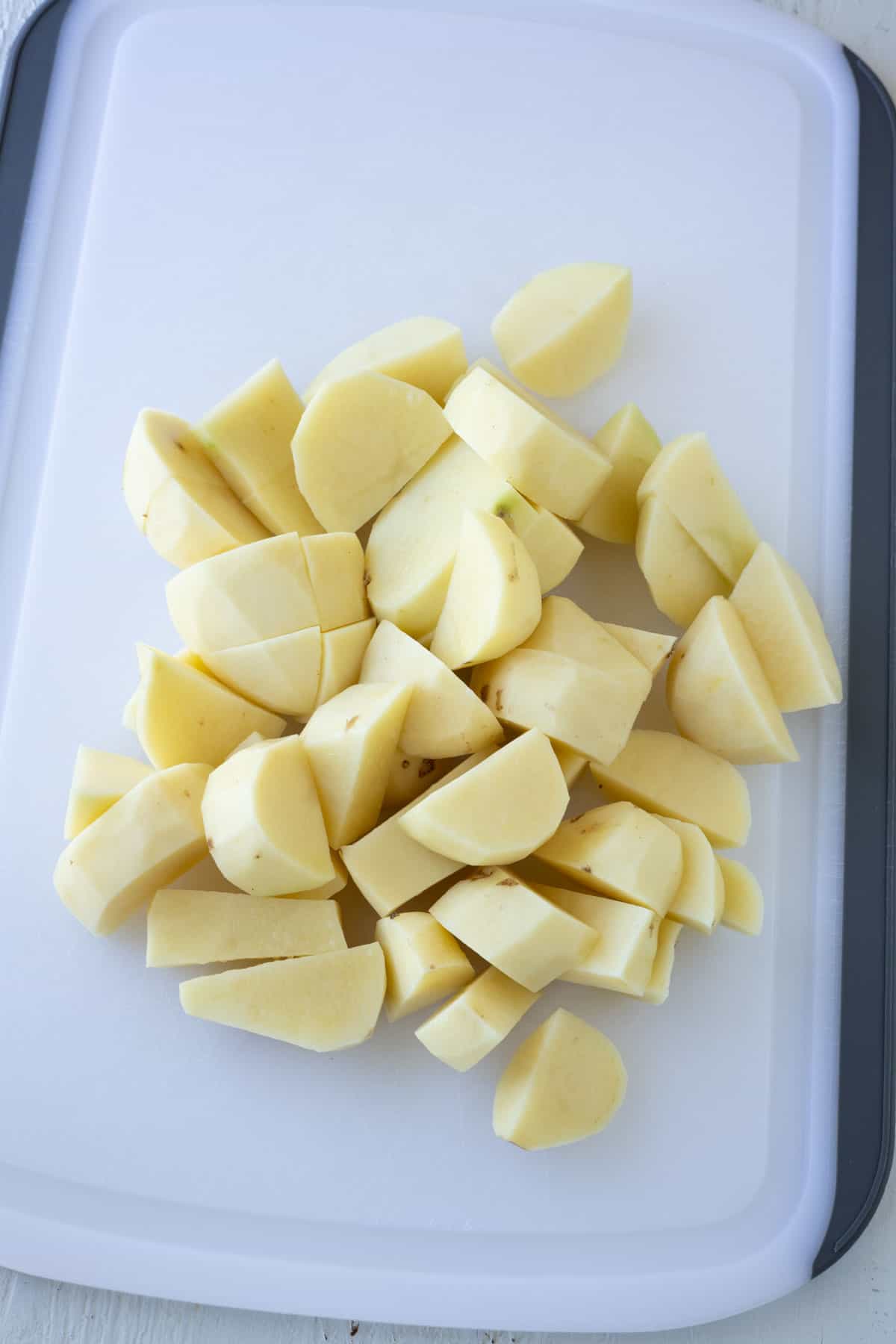 Peeled and diced potatoes on a cutting board.