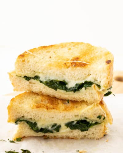 A grilled cheese sandwich with mozzarella cheese and fresh spinach.