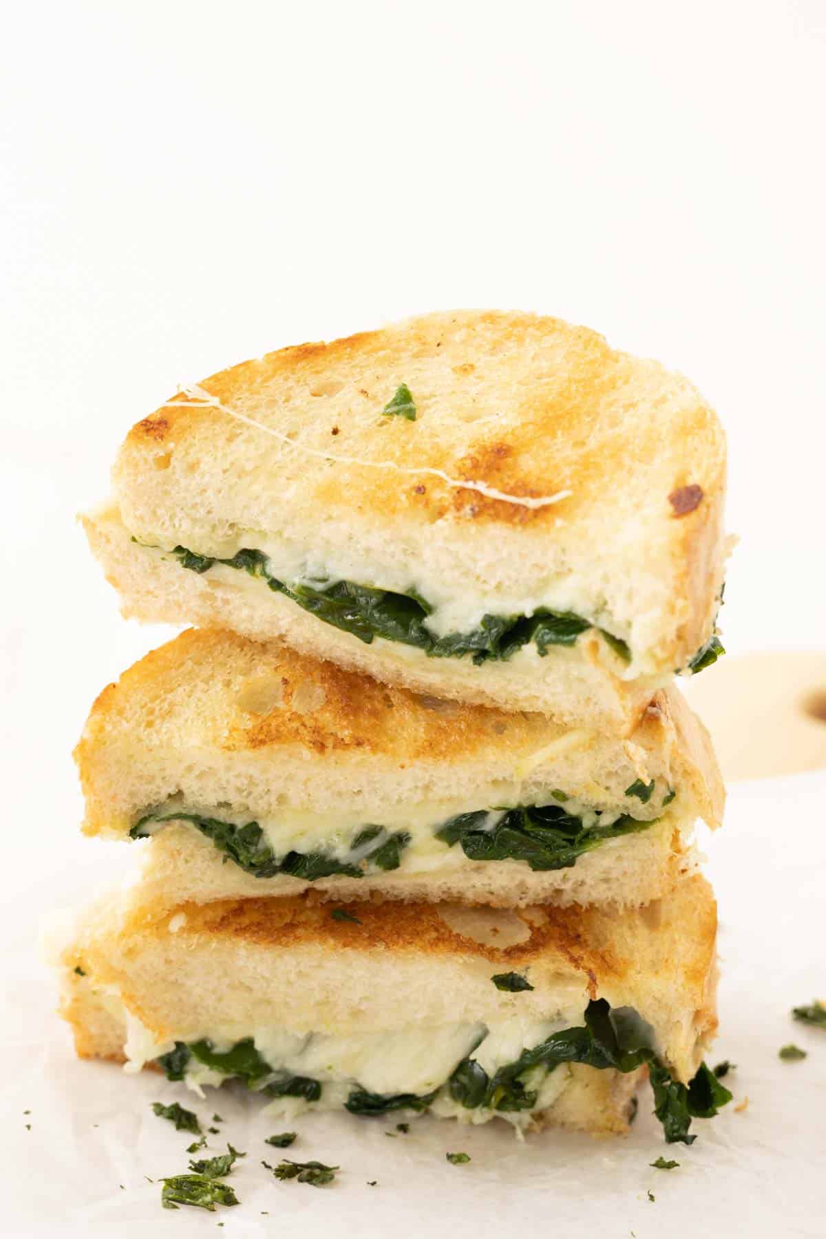 A stack of grilled cheese sandwiches with spinach.