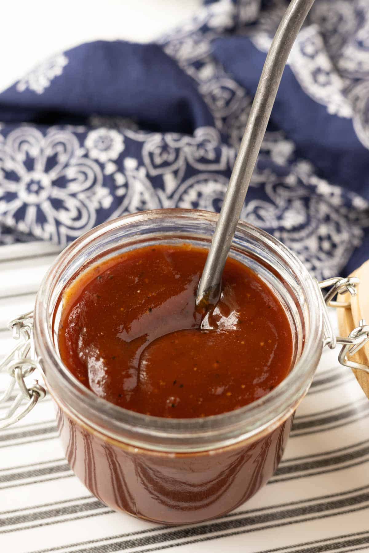 BBQ sauce in a glass jar with a spoon.