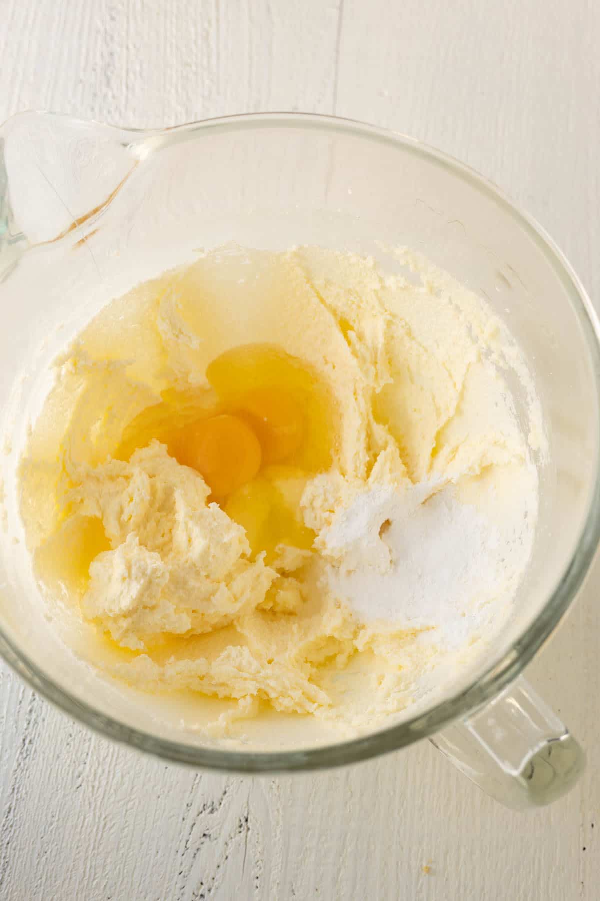 A large mixing bowl with creamed butter and sugar with eggs, vanilla, and baking powder, baking soda, and salt. 