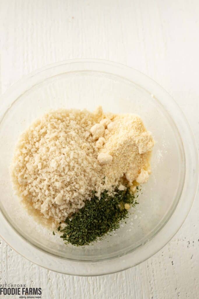 A bowl with panko bread crumbs, parmesan cheese, and parsley.