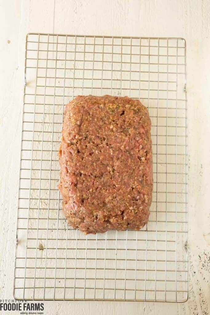 Raw meatloaf on a wire rack.