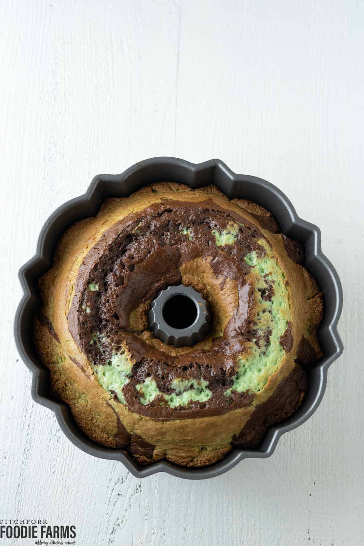 A swirled pistachio bundt cake with green and chocolate marble.