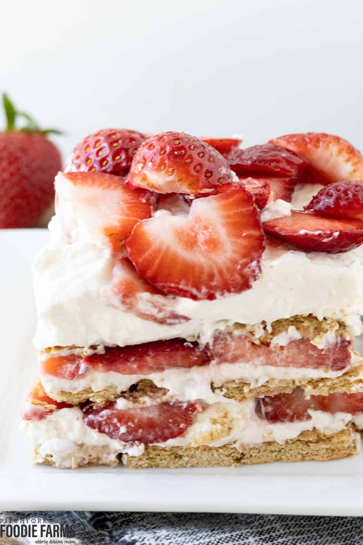 A piece of strawberry icebox cake with cheesecake, graham cracker, and fresh strawberry layers.