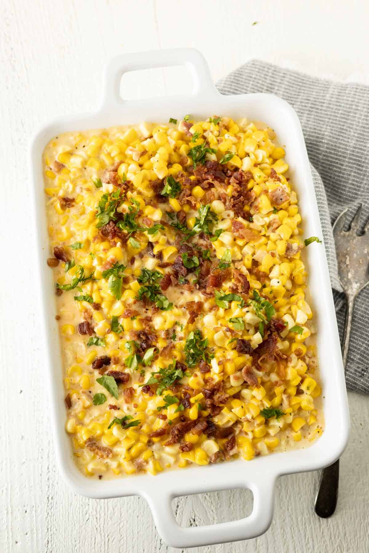 Corn casserole with cheese in a white baking dish.