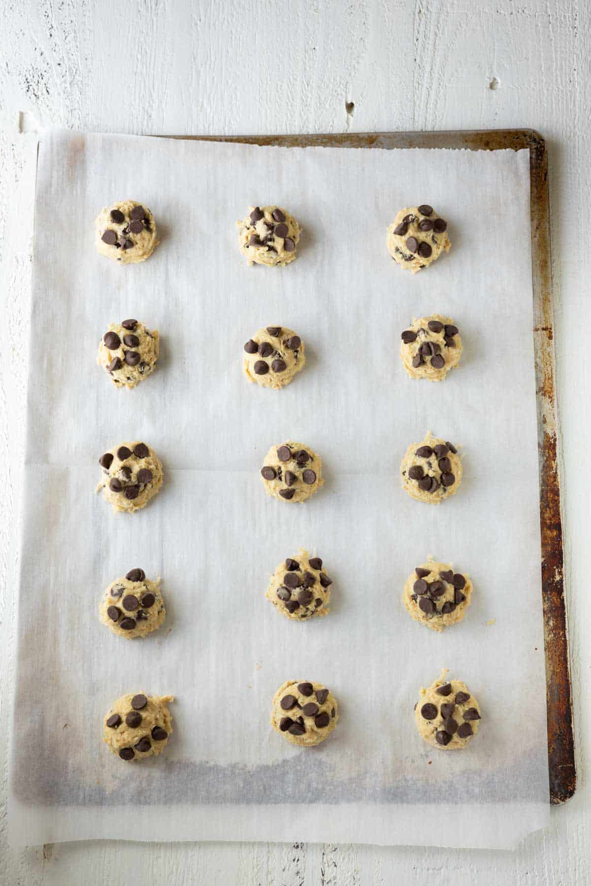 Coconut chocolate chip cookie dough balls on a baking sheet.