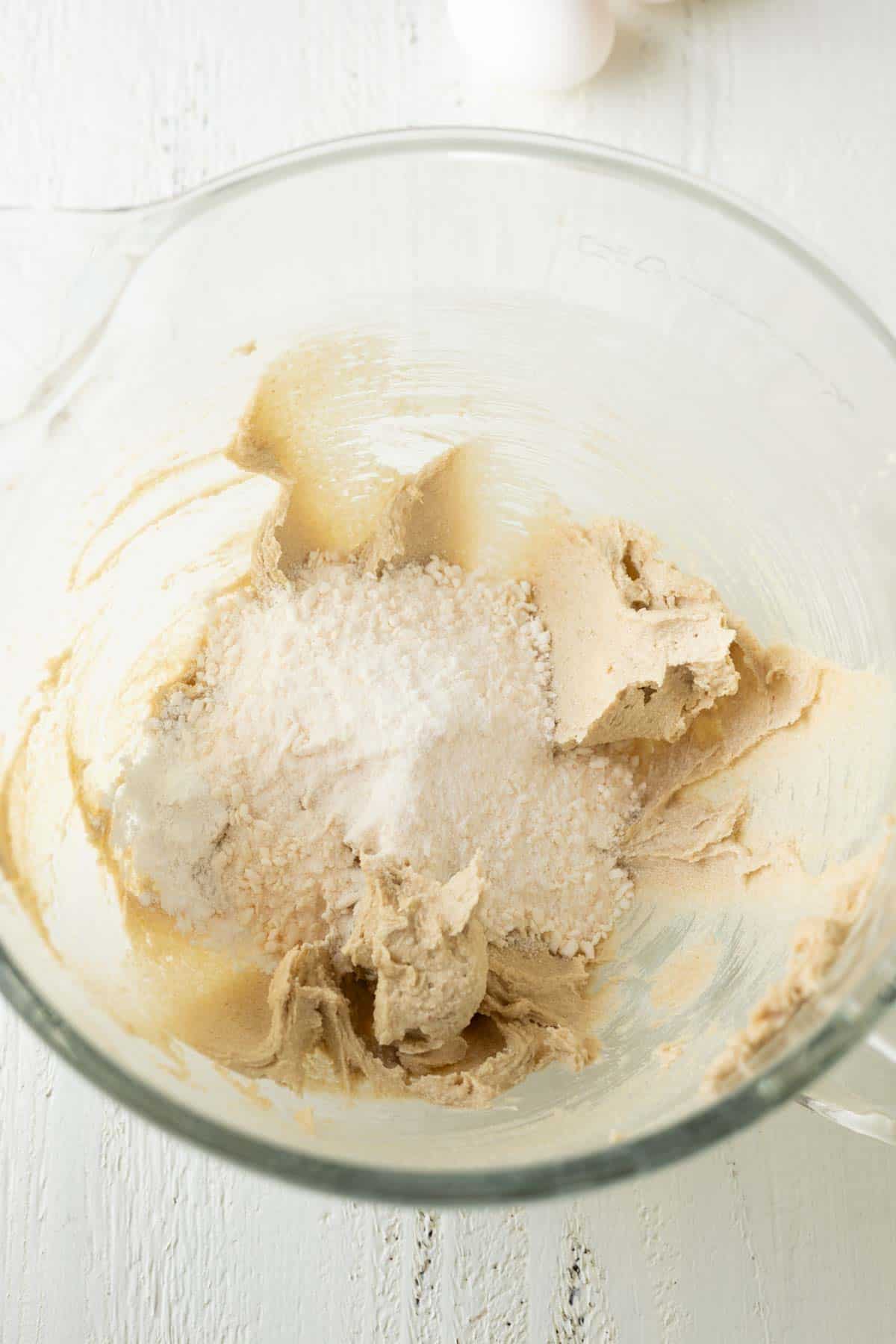 A glass mixing bowl with creamed butter, sugar, with instant pudding mix.