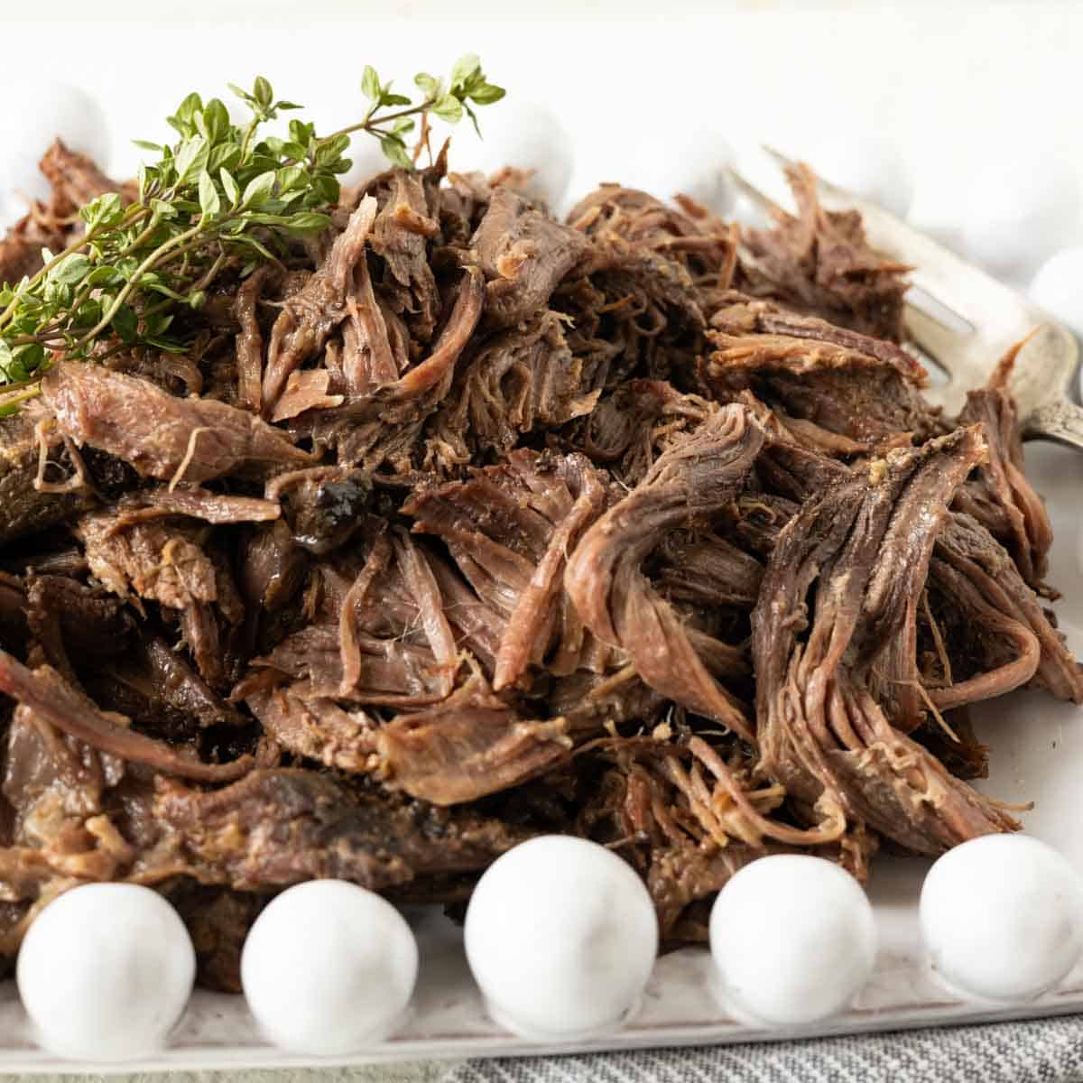 A white plate with shredded roast beef.