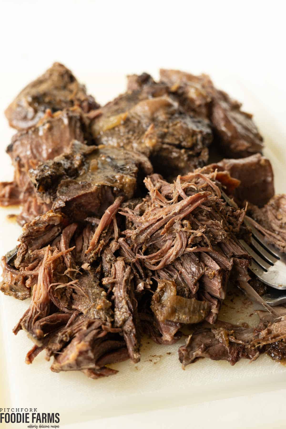 Shredded roast beef on a cutting board.