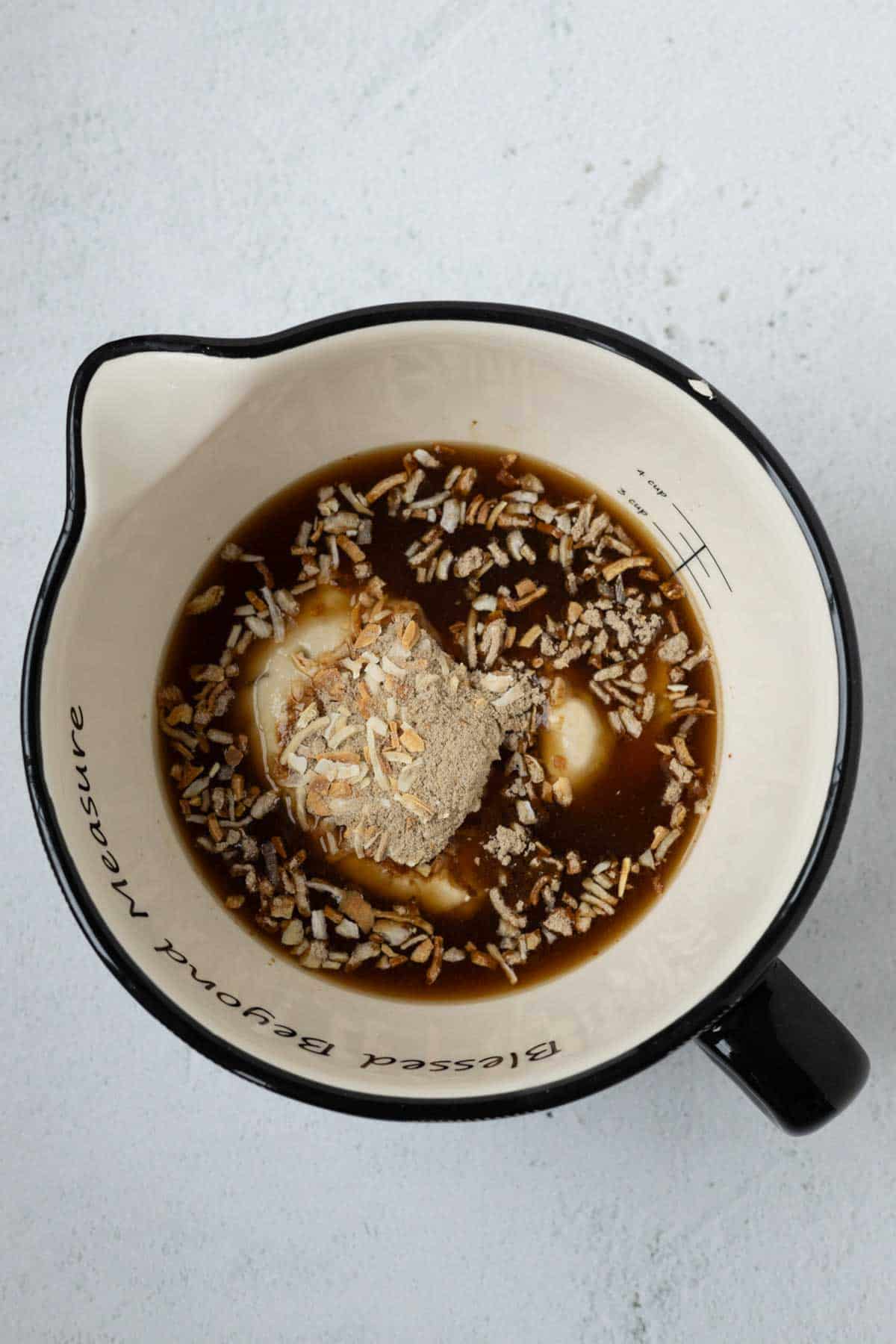 A mixing bowl with cream of mushroom soup, onion soup mix, and beef broth.