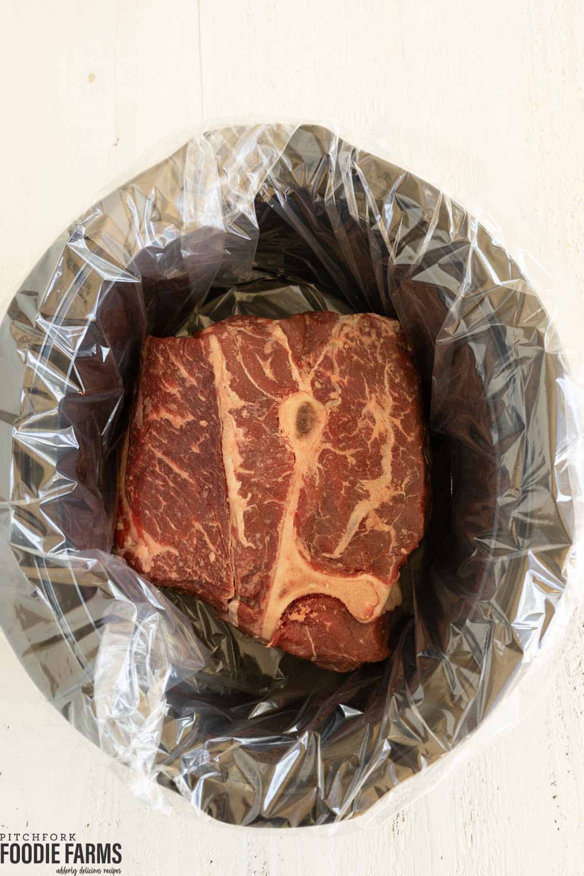 An uncooked chuck roast in a slow cooker. 