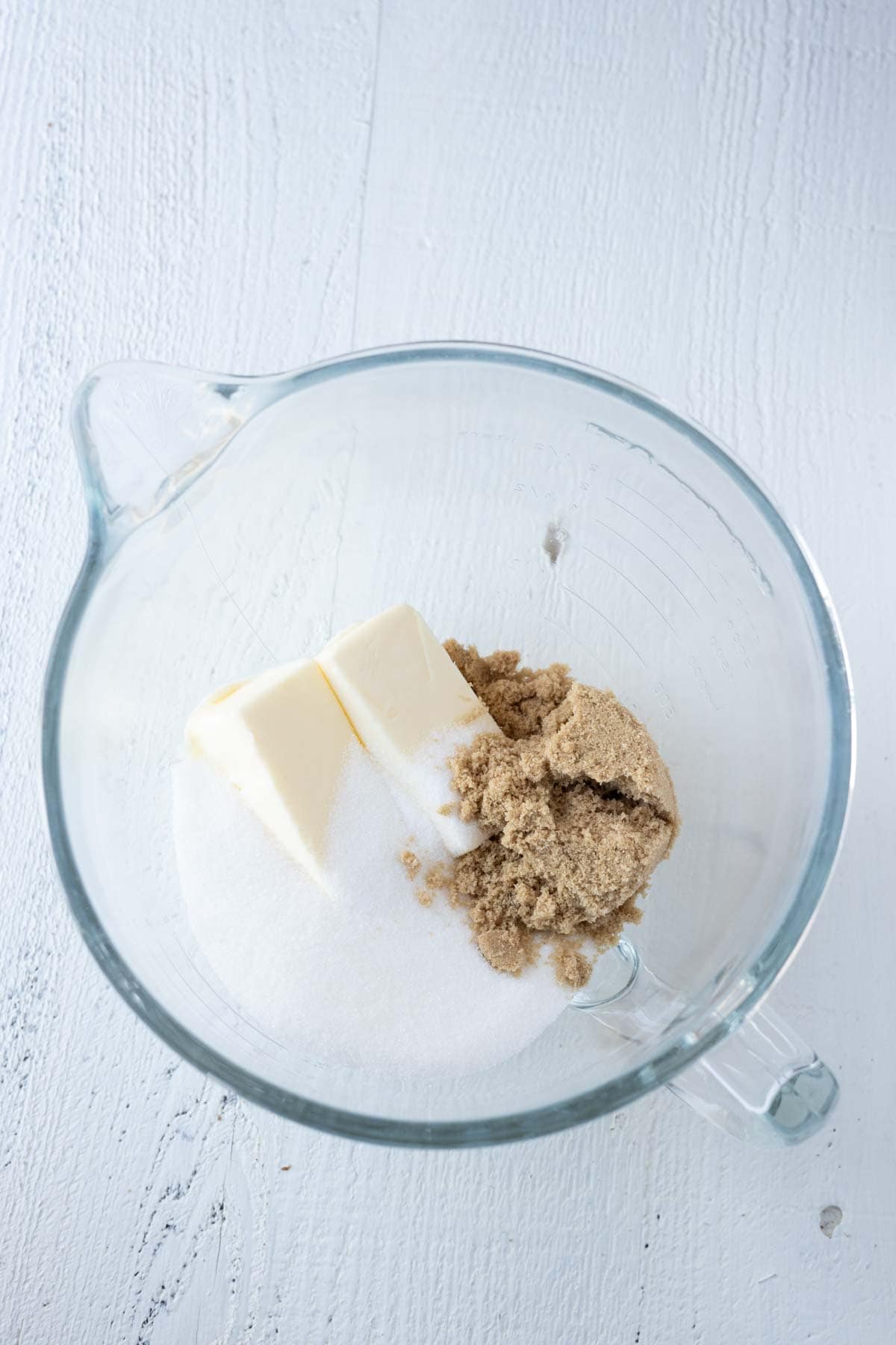Butter, brown sugar and white sugar in a glass mixing bowl.