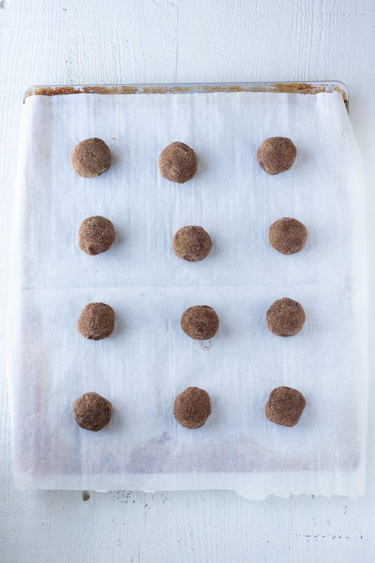 Chocolate snickerdoodle cookie dough on a parchment paper lined cookie sheet.