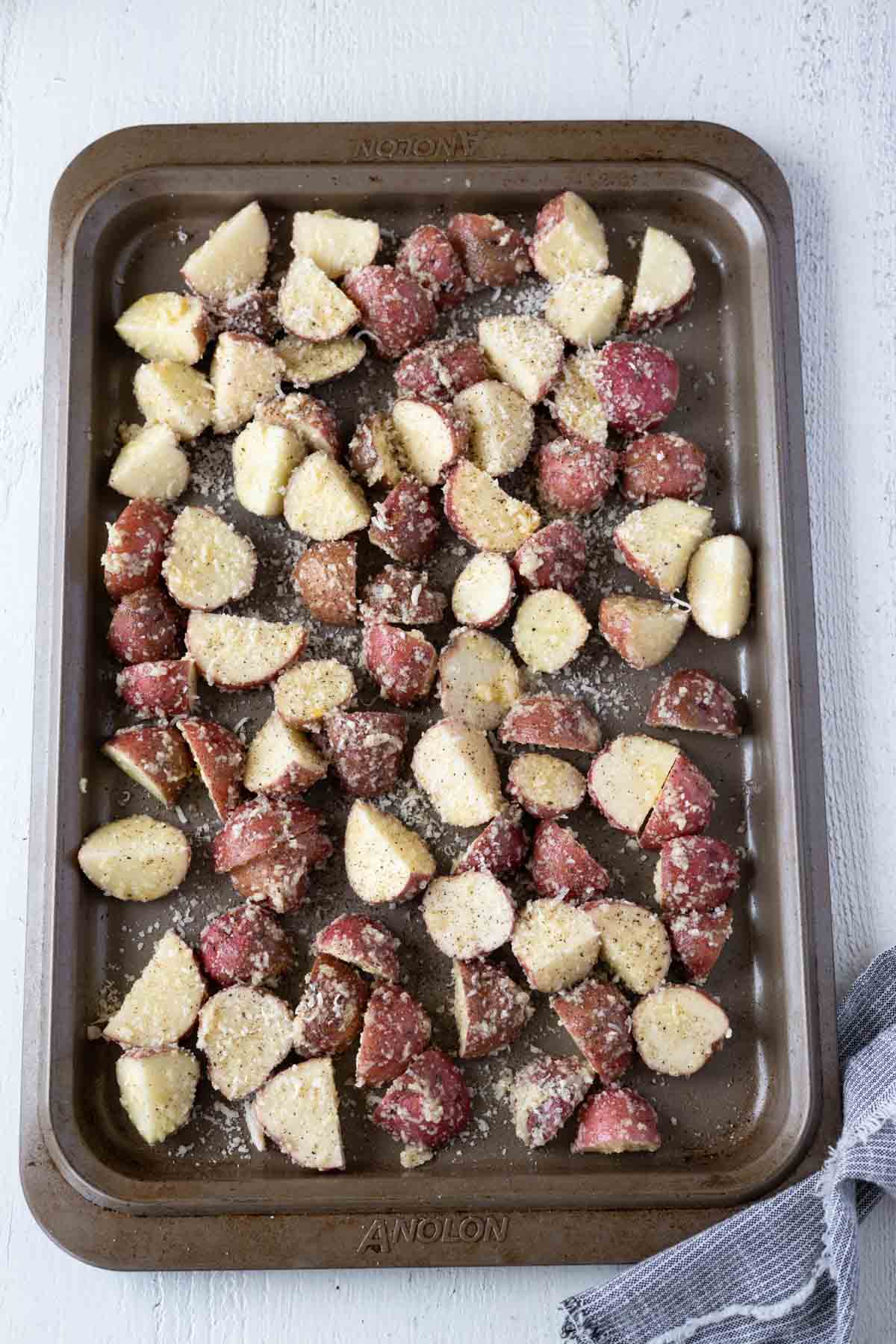 Red potato chunks in a sinlge layer on a baking sheet.